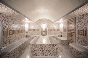 Um banheiro luxuoso com paredes de azulejo em mosaico, uma pia central de mármore e um espaço de estar.