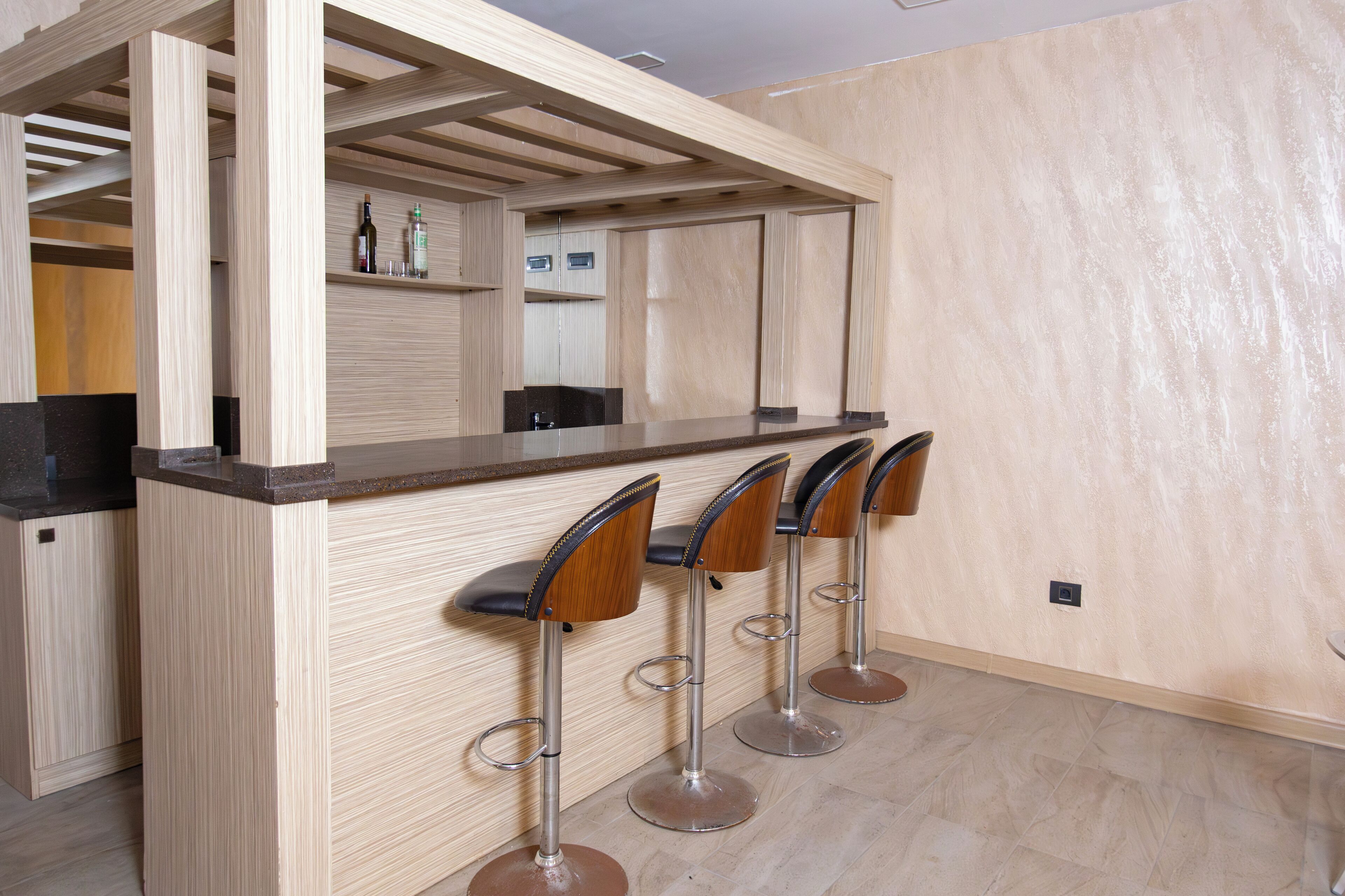 A bar area with a wooden counter and four bar stools.