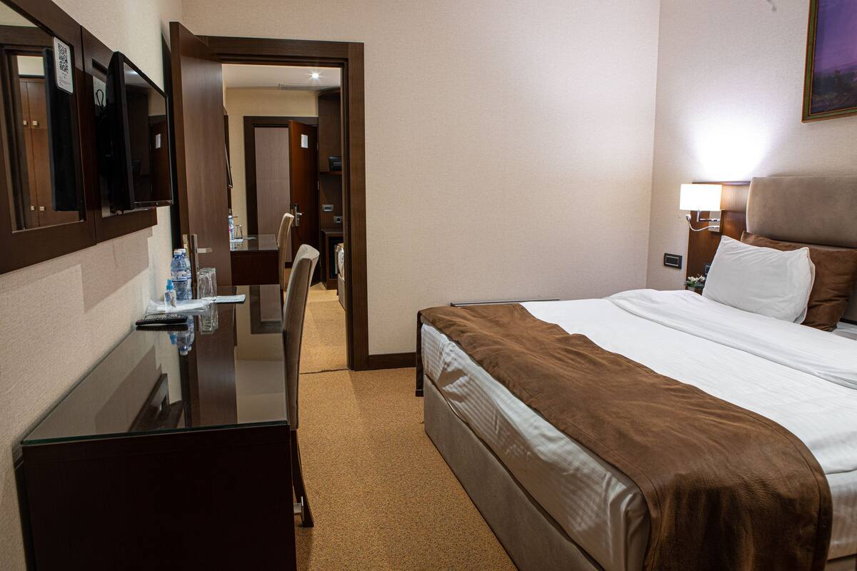 A hotel room with a bed, a desk, and a mirror.