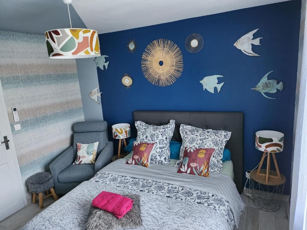 A bedroom with a bed, a chair, a lamp, and wall decorations.