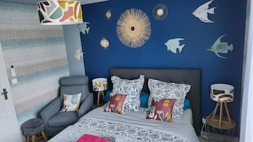 A bedroom with a bed, a chair, a lamp, and wall decorations.