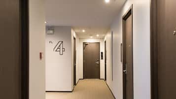 A hotel hallway with a carpeted floor, wooden doors, and a wall-mounted sign indicating room number 4A.