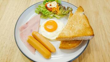 A plate with a sandwich, two hot dogs, a fried egg, and a side salad.