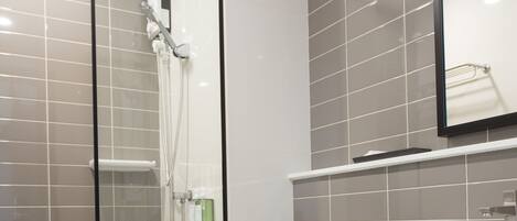 Un baño moderno con ducha de vidrio, inodoro blanco y lavamanos grande.