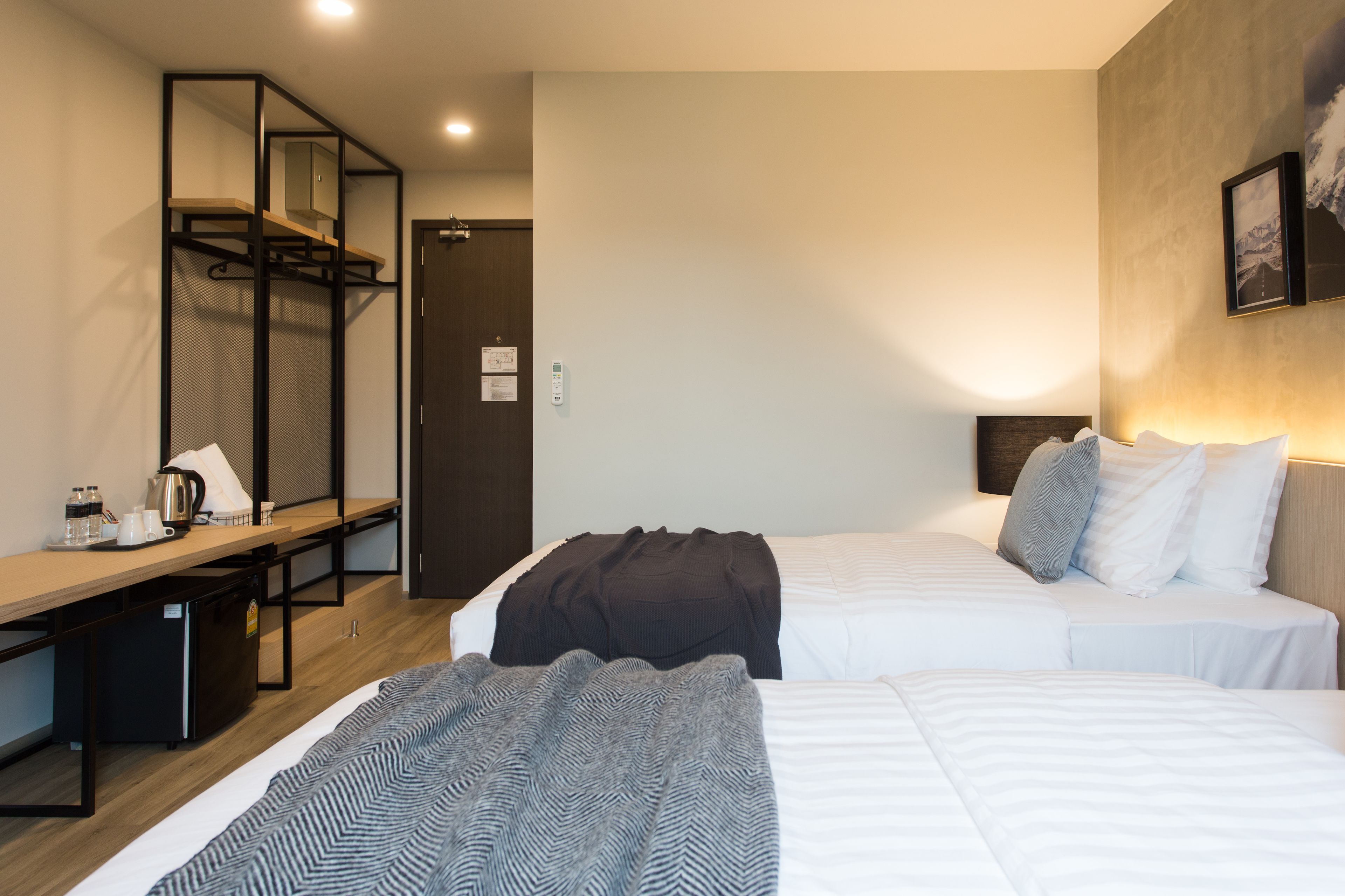 A hotel room with two beds, a desk, a mirror, and a wardrobe.