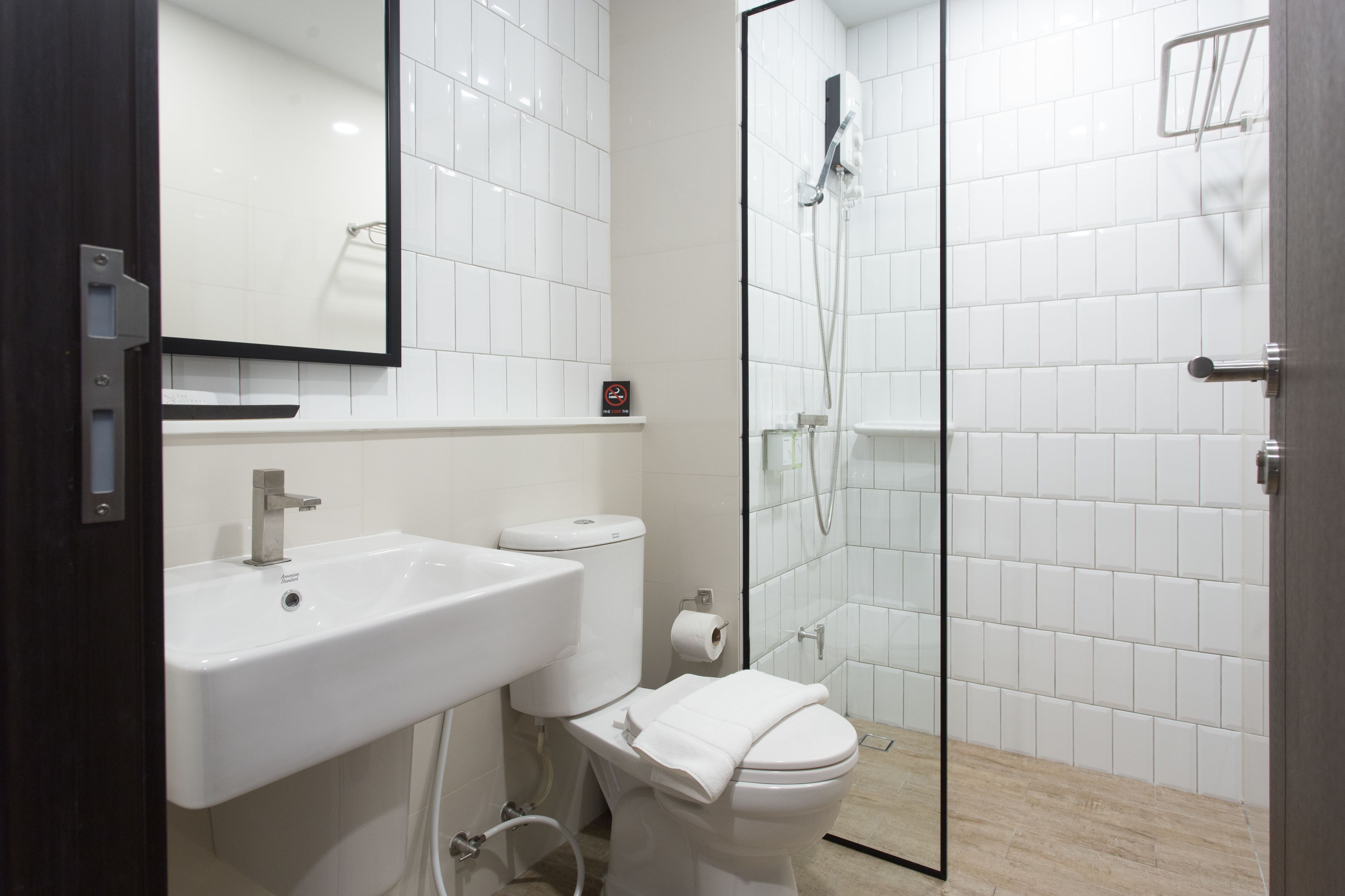 A modern bathroom with a white sink, toilet, and glass-enclosed shower.