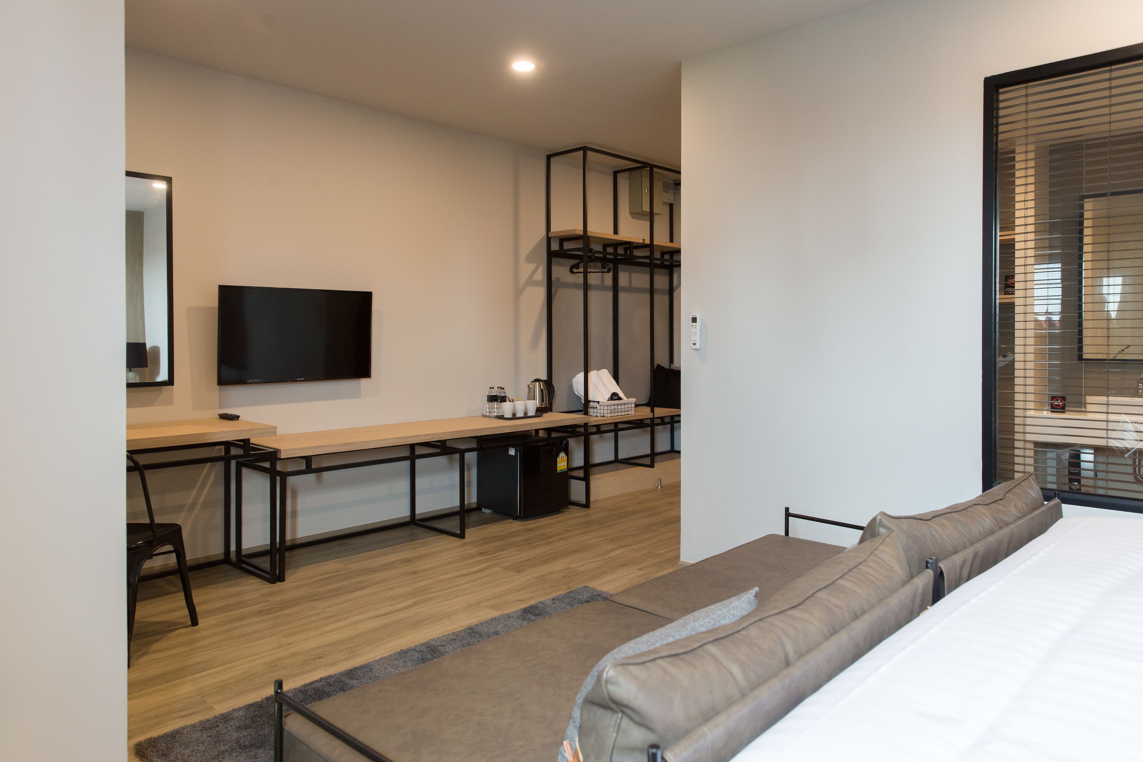 Una habitación de hotel moderna con una cama, un escritorio con una computadora, televisión y una kitchenette.