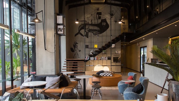 Een modern interieur met een rond zitgedeelte, een trap en een groot raam dat voor natuurlijk licht zorgt.