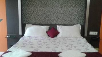 A neatly made bed with a floral-patterned bedspread, two white pillows, and a single red accent pillow.