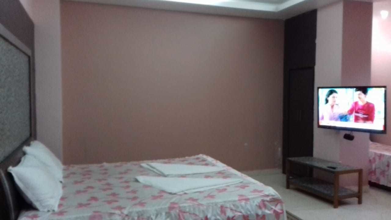 A hotel room with a bed, a television, and a small table.