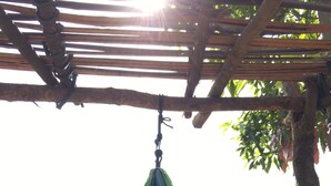 A hammock under a wooden pergola with a view of a mountainous landscape.