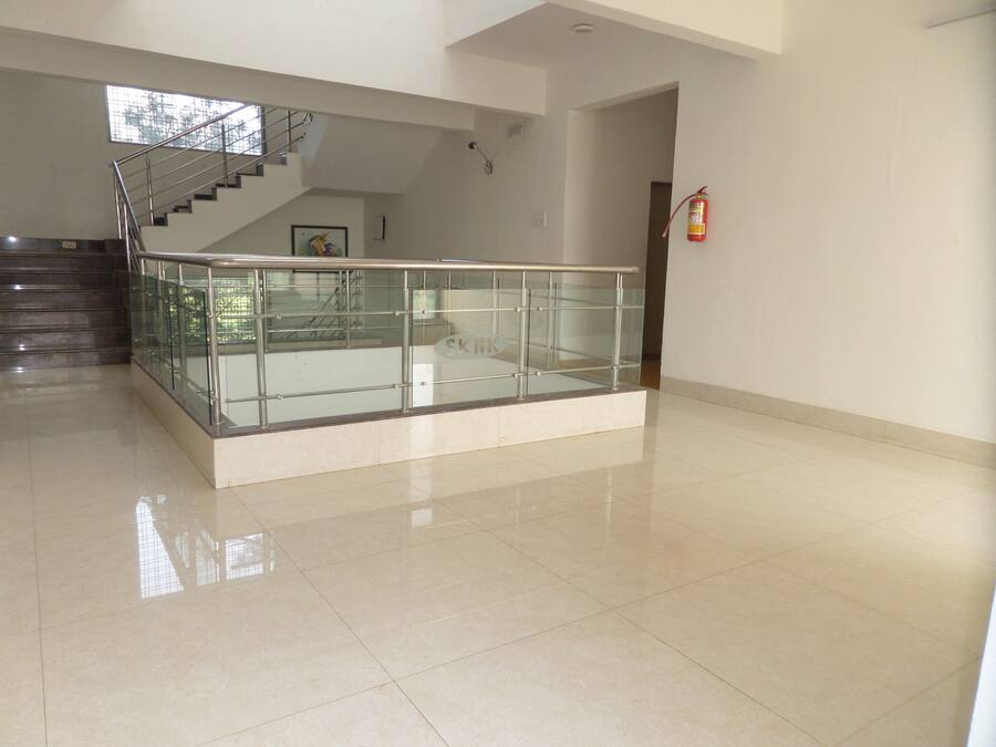 Un espacio interior amplio con barandilla de vidrio, una escalera y un extintor en la pared.