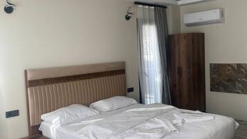 Ein modernes Schlafzimmer mit einem großen Bett, einem Nachttisch aus Holz, einem Kleiderschrank und einer Klimaanlage an der Wand.