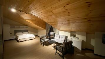 Une chambre confortable située sous les combles, avec un plafond en bois, un lit, un canapé et une table à manger.
