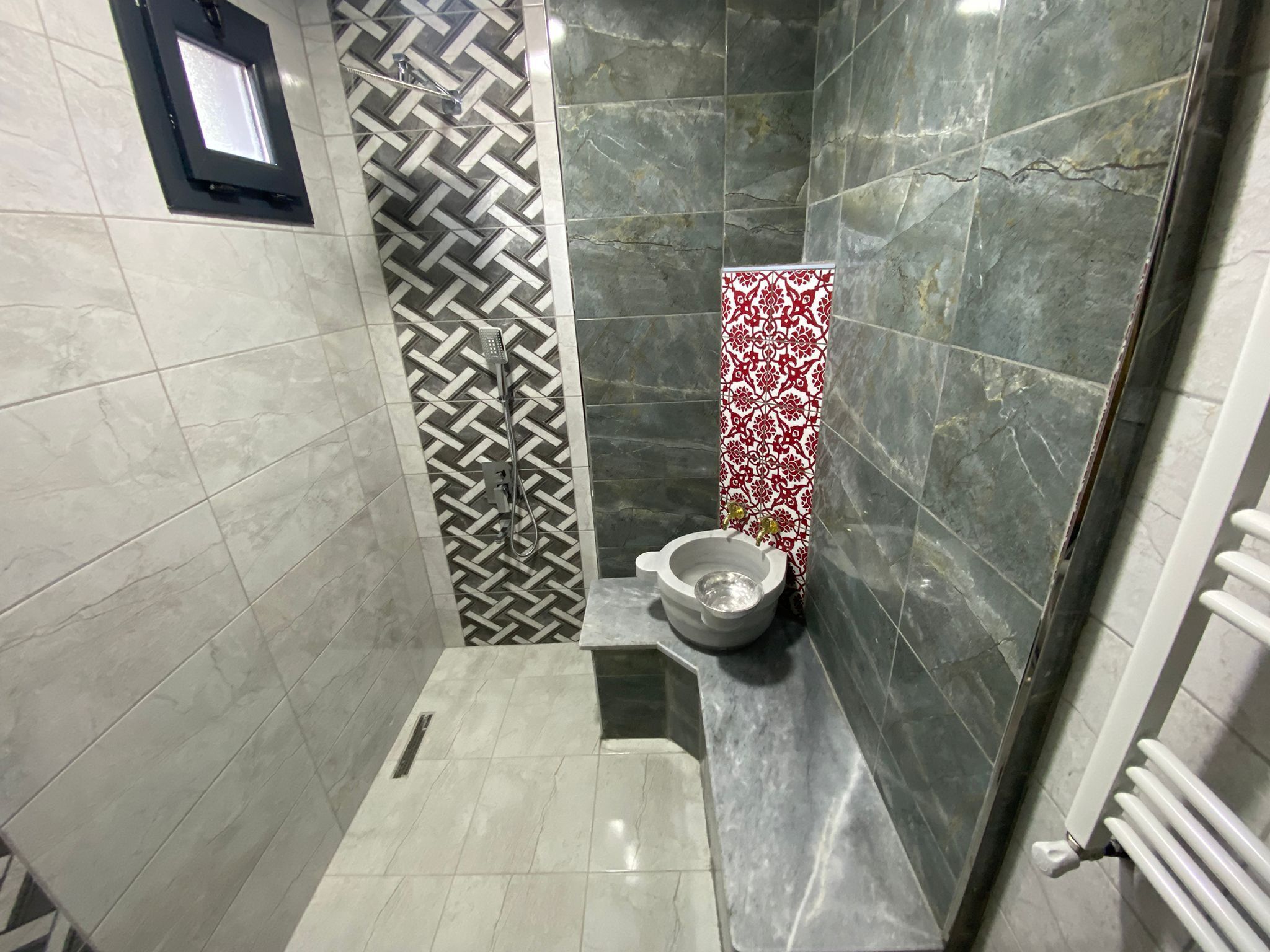 A bathroom with a shower, toilet, and a small window.