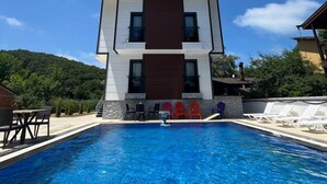 A modern two-story building with a swimming pool in front.