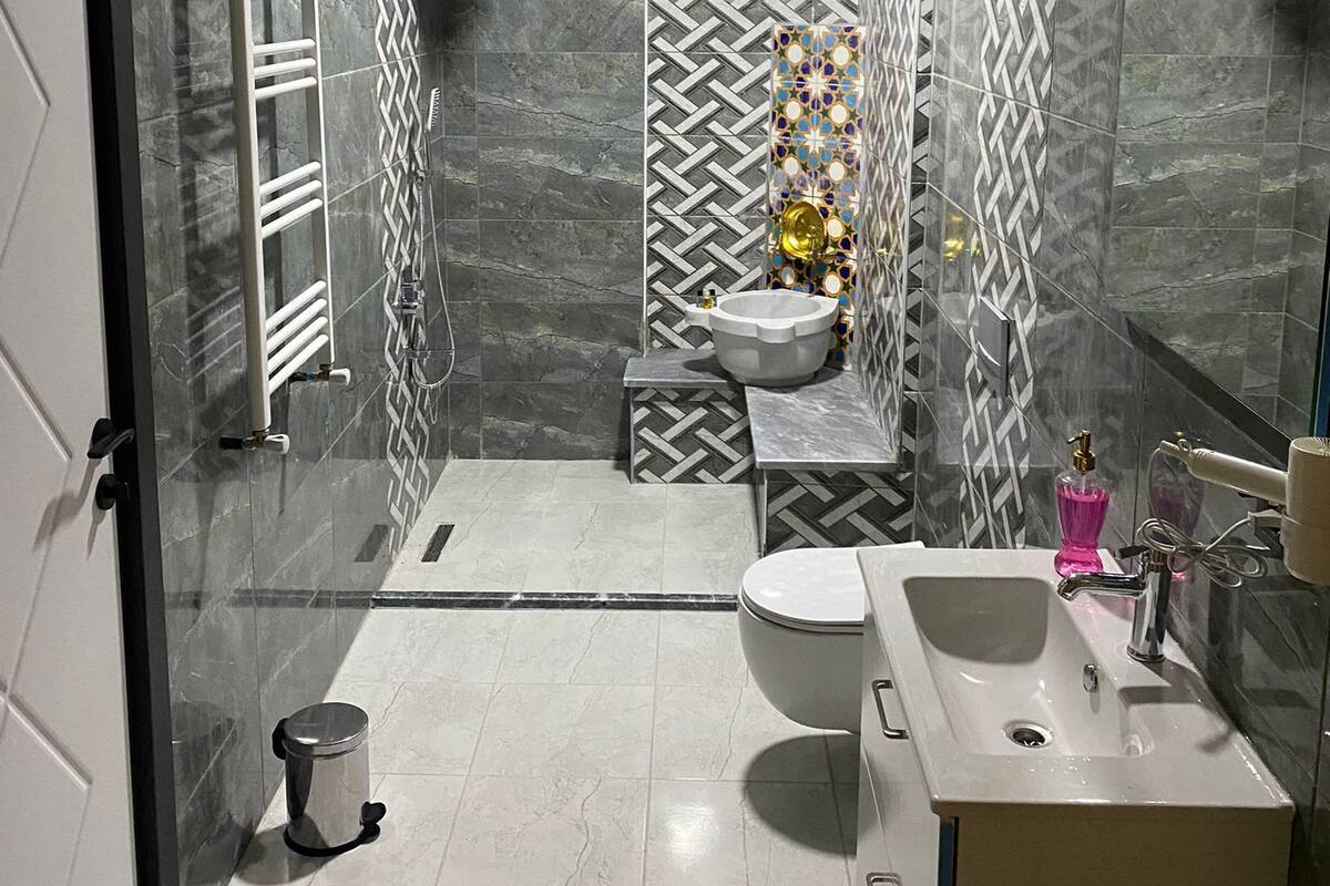 Ein modernes Badezimmer mit einem großen Spiegel, einem Waschbecken, einer Toilette und einer Duschkabine.