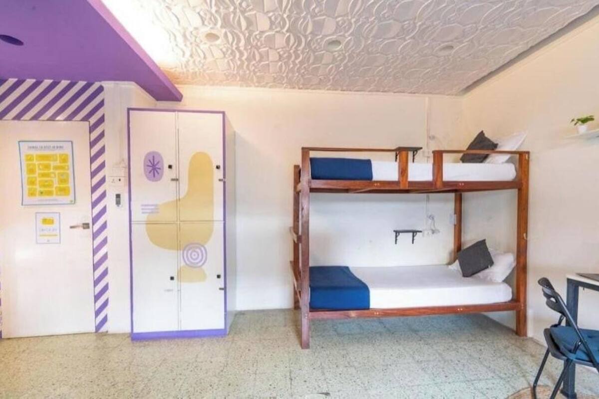 A room with bunk beds, a wardrobe, and a desk.