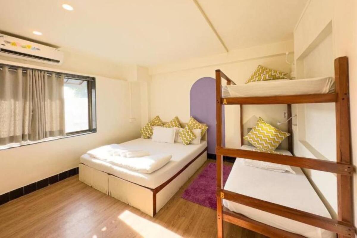 A bedroom with a single bed, a bunk bed, a window with curtains, and an air conditioning unit.