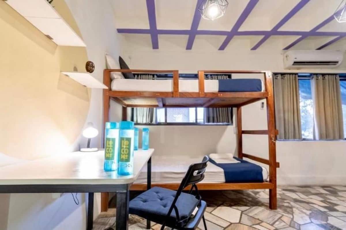 A bunk bed room with a desk, chair, and storage cabinets.