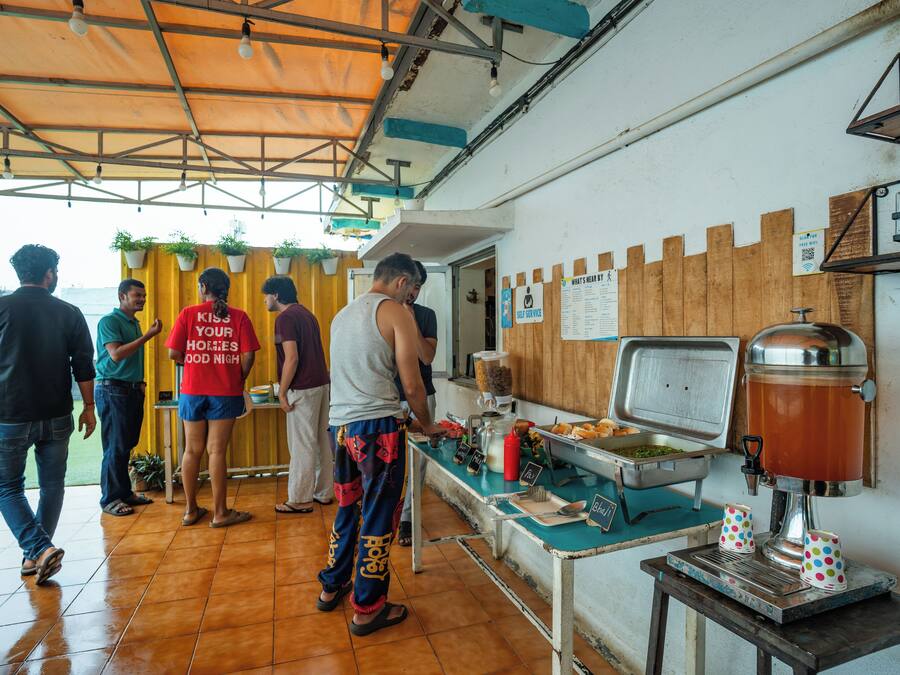 Zona de comida con una máquina de café, una mesa de buffet y un letrero que indica servicio propio.