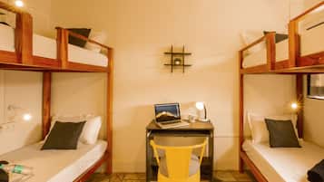 Quarto com duas camas de solteiro sobrepostas, uma mesa com um laptop e uma cadeira.