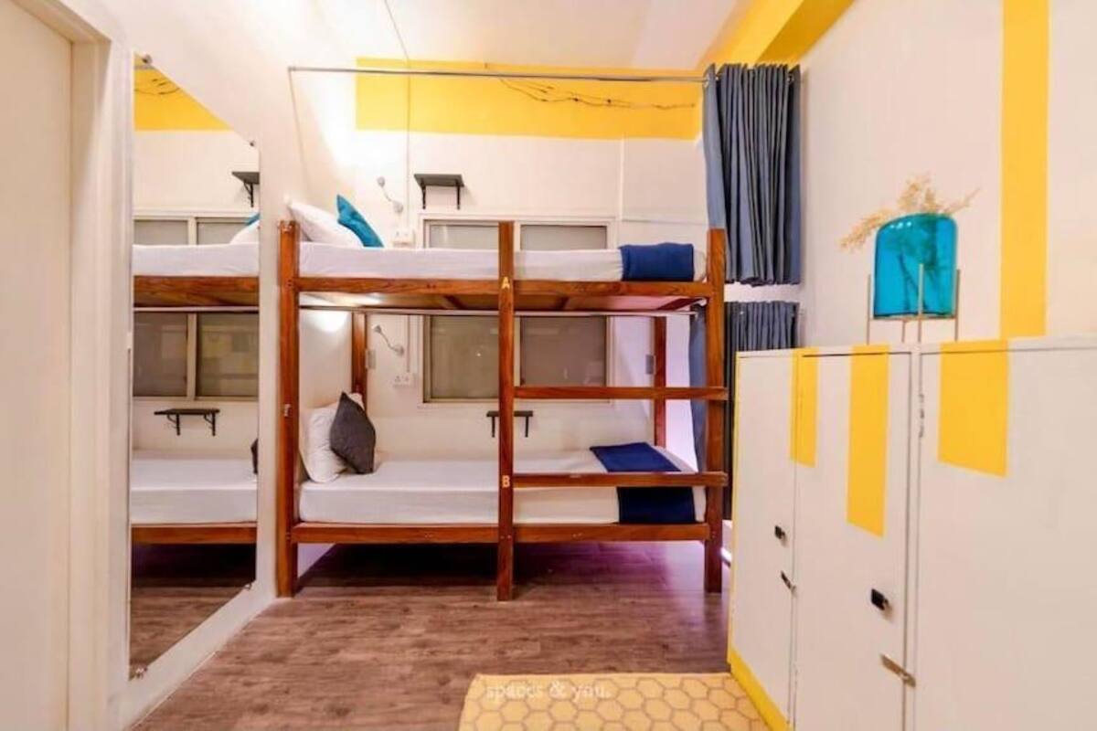 A dormitory room with bunk beds, a window, and a wardrobe.
