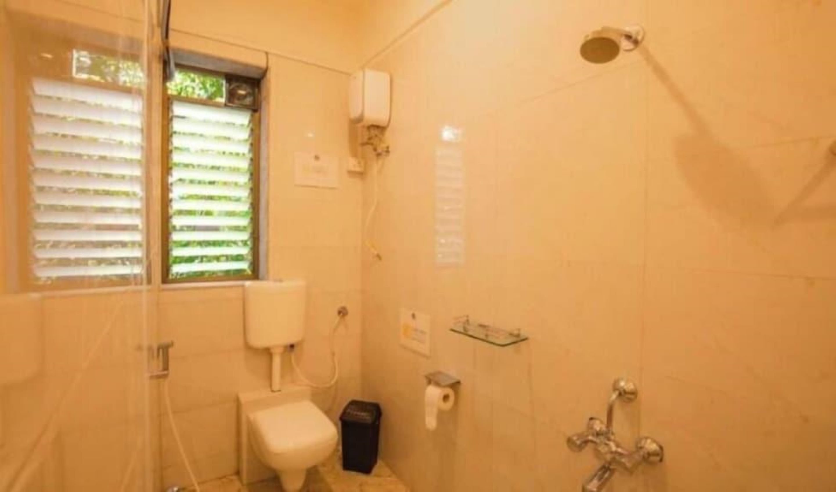A bathroom with a toilet, a shower, and a window with blinds.
