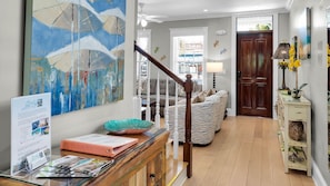 Una sala de estar con una escalera, un sofá, una mesa de centro y un cuadro en la pared.