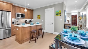 A modern kitchen with wooden cabinets, stainless steel appliances, and a central island with stools. - **THE TOASTED COCONUT @ OLD TOWN** Pool + Last Key White Glove Service... (Key West)