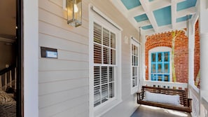 A hallway with a white exterior, a brick wall with a blue window, and a wooden bench with a white towel. - **THE TOASTED COCONUT @ OLD TOWN** Pool + Last Key White Glove Service... (Key West)