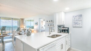 A modern kitchen with a large island, white cabinetry, and a view of the ocean.