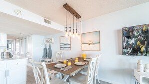 A dining area with a wooden table, white chairs, and a modern pendant light.