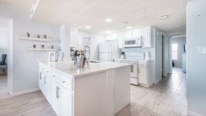A modern kitchen with white cabinetry, a central island, and built-in appliances.