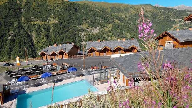 A mountain lodge with multiple wooden cabins, a swimming pool, and a parking area. - Chalet in French Alps with Scenic Views (VALMEINIER)
