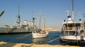 Un porto con una grande nave da guerra ormeggiata accanto a una barca più piccola.