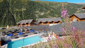 Un rifugio di montagna con diverse cabine in legno, una piscina e un’area parcheggio.