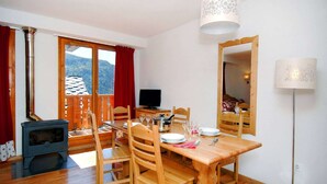 Un'accogliente zona pranzo con un tavolo e sedie di legno, una televisione e un camino a legna.