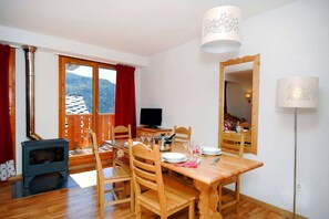 Ein gemütlicher Essbereich mit Holztisch und -stühlen, einem Fernseher und einem Holzofen.