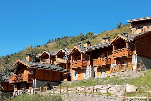 Una fila di cabine di legno con fondamenta in pietra e balconi in legno, sotto un cielo sereno.