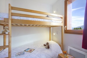 A bunk bed room with a window, a stuffed toy, and some books.