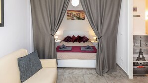 Una camera da letto con un letto, tende, un divano e una parete con un quadro.
