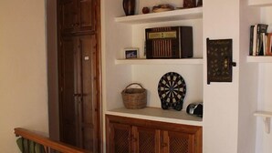 A room with wooden cabinets, a dartboard, a radio, and a basket on shelves.