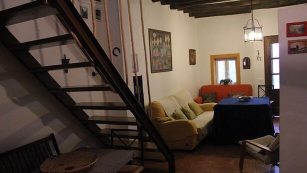A cozy living room with a staircase, a sofa, a table, and a window.