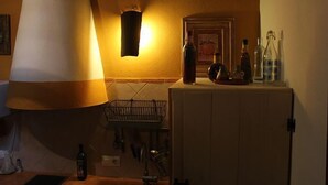 A dimly lit room with a large floor lamp, a small table with a bottle, and a cabinet with bottles on top.