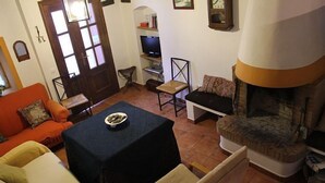 A cozy living room with a fireplace, a sofa, a table with a bowl, and a television in the background.