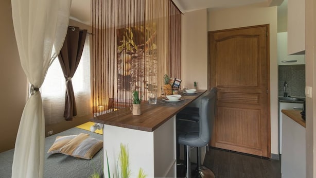 A compact kitchen with a wooden counter, a dining area with a chair, and a large wooden door. - Kazette - Your Holiday Studio on Reunion Island (L'Étang Saint-Louis)