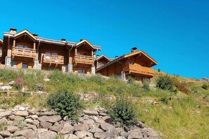 A wooden chalet with multiple balconies, set on a hillside with a clear blue sky. - Rustic apartment with dishwasher in Valmeinie (VALMEINIER)