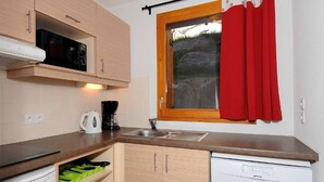 Uma cozinha compacta com micro-ondas, máquina de café, pia e lava-louças.