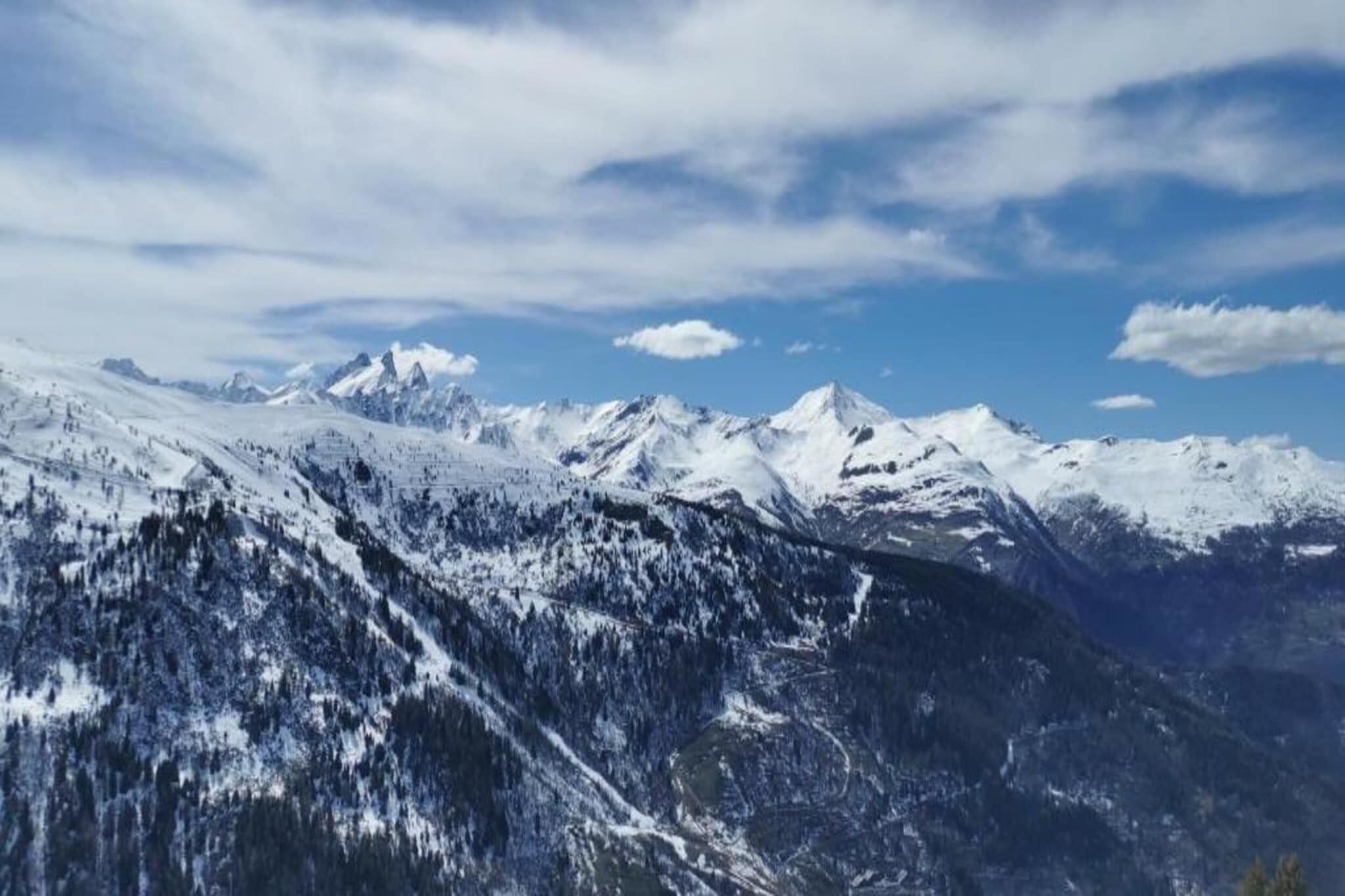 A mountainous landscape with snow-covered peaks and a clear sky.